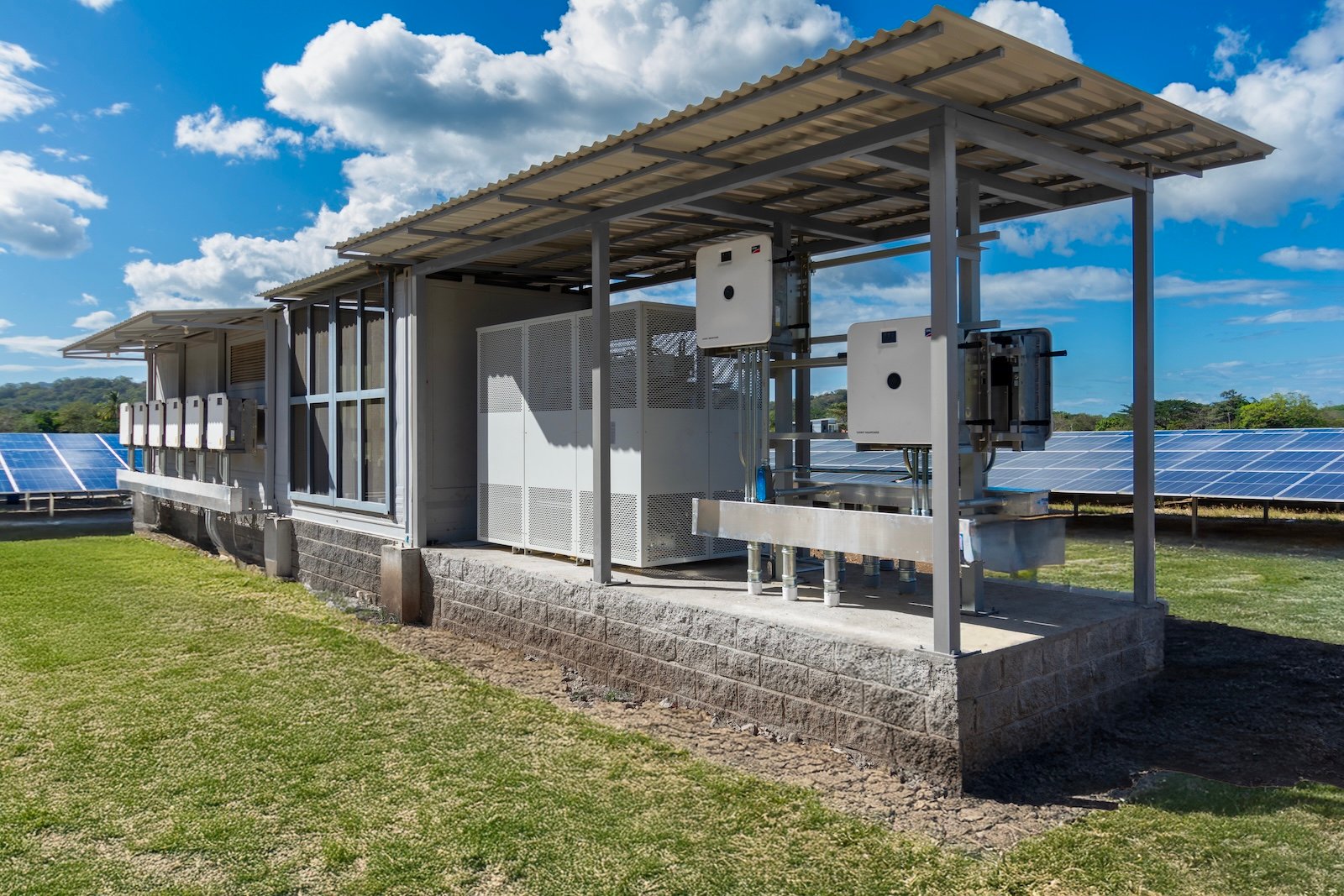 Equipos eléctricos de un sistema de energía solar empresarial junto a paneles fotovoltaicos en Costa Rica.